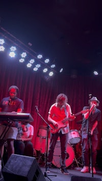 a group of people playing music on stage in front of a red light